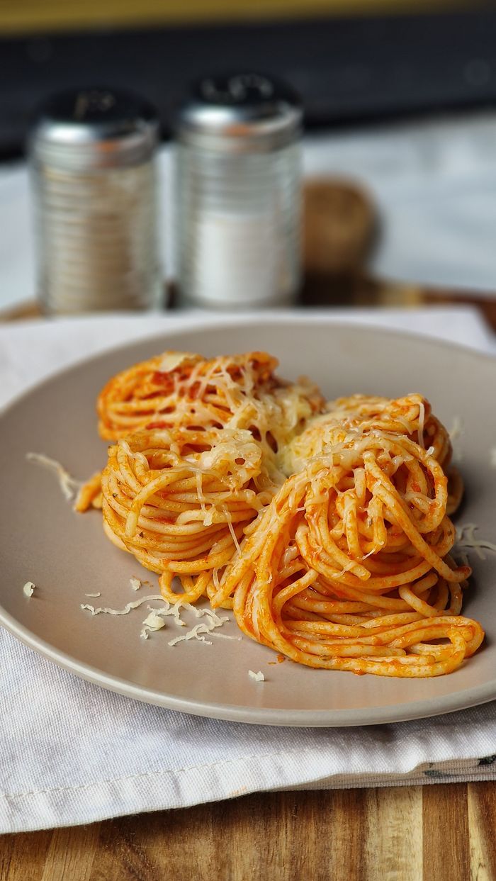about-us-01 Plate of spaghetti topped with tomato sauce and grated cheese, perfect for Italian cuisine lovers.