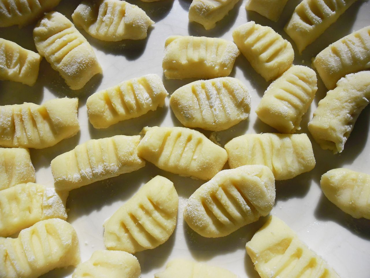 services-01 Close-up of fresh homemade gnocchi pasta arranged on a flour-dusted surface, ready for cooking.