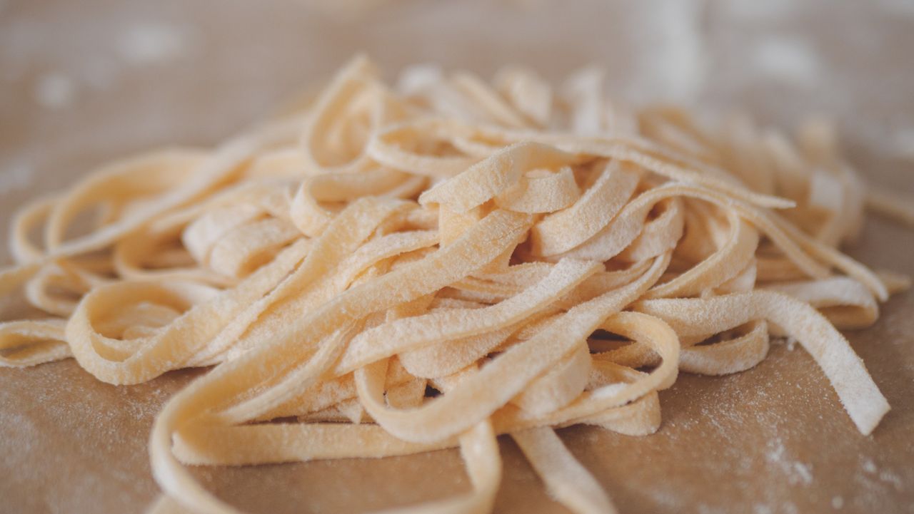 about-us-01 A detailed shot of freshly made uncooked noodles on a floured surface.