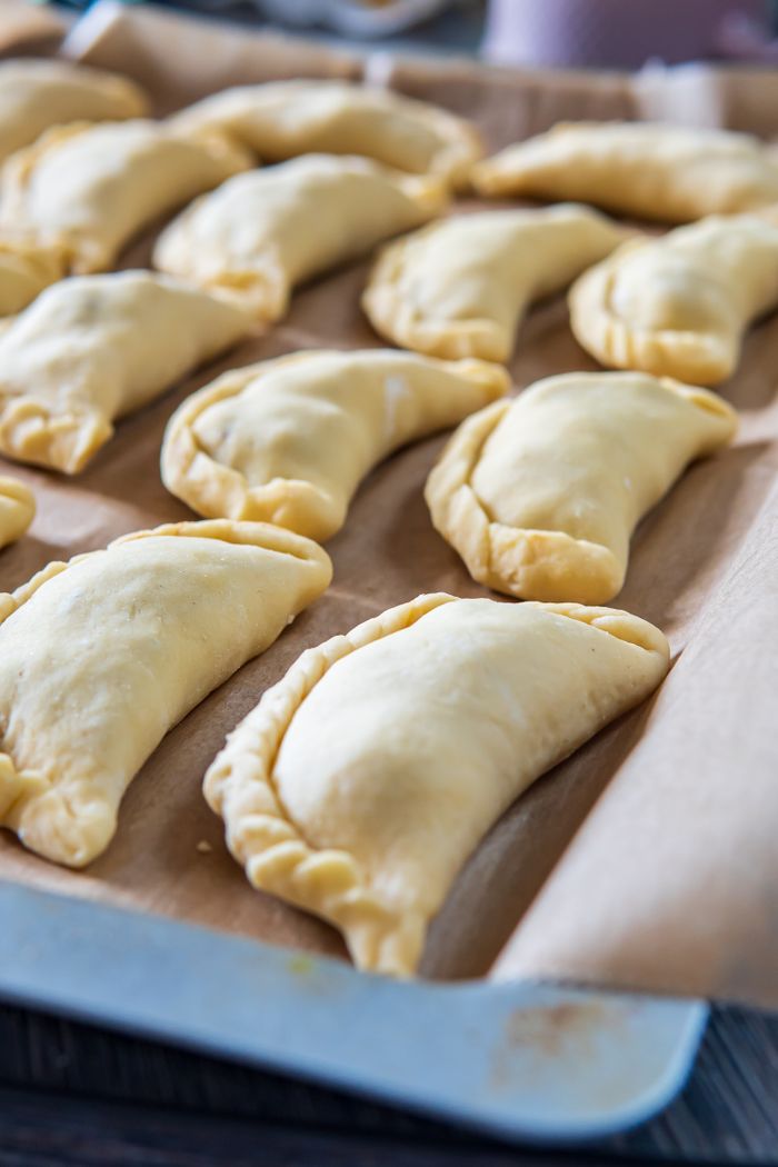 services-03 Fresh uncooked empanadas arranged on a baking tray, ready for the oven.